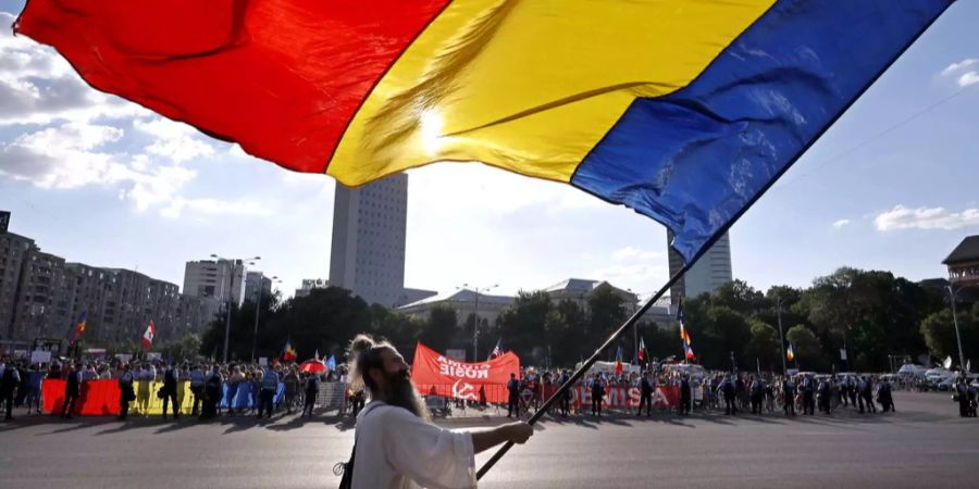 Ein Mann schwenkt die rumänische Flagge während einer Demonstration in Bukarest.