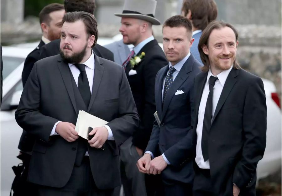 Die Schauspieler John Bradley (l-r), Joe Dempsie und Ben Crompton stehen nach der Trauung von Rose Leslie und Kit Harington vor der Kirche.