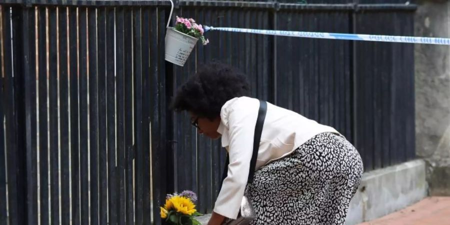Eine Frau legt zum Gedenken an die Opfer im Stadtzentrum von Reading Blumen nieder. Foto: Jonathan Brady/PA Wire/dpa