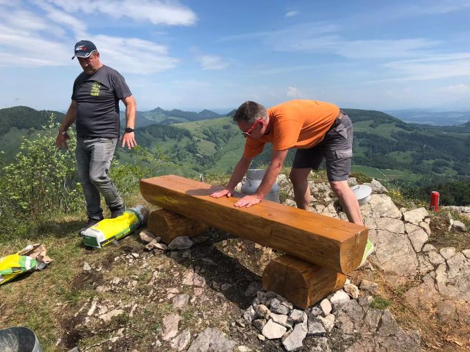 Die Männer beim Platzieren der neuen Sitzbank. Sitzbank Vogelberg Mümliswil