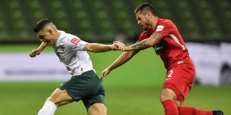 Werder-Profi Milot Rashica (l) wird vom Heidenheimer Marnon Busch verfolgt. Foto: Martin Meissner/AP POOL/dpa