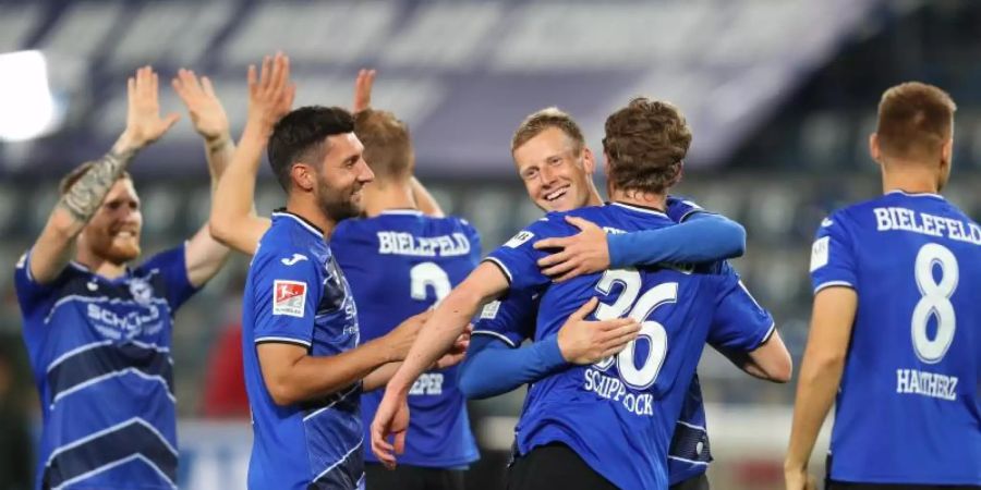 Brian Behrendt (2.vr) von Arminia Bielefeld feiert mit Sven Schipplock und weiteren Mitspielern den Sieg. Foto: Friso Gentsch/dpa-pool/dpa