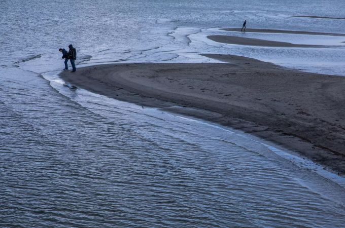 Spaziergänger sind bei wechselhaftem Wetter am Ostseestrand unterwegs. Spaziergänger an der Ostsee