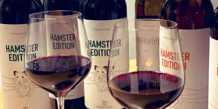 Zwei gefüllte Weingläser und Flaschen der «Hamster Edition» stehen auf einem Tisch beim Weingut Diehl. Foto: Weingut Diehl/dpa