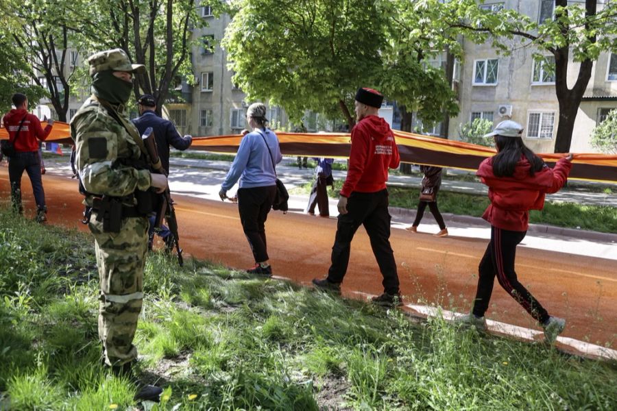 Menschen tragen ein Sankt-Georgs-Band durch Mariupol.