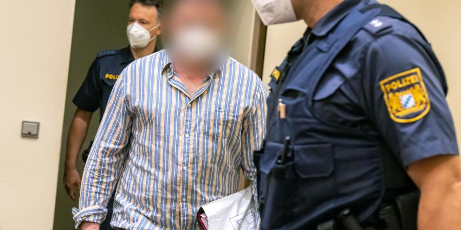 Der Angeklagte wird von der Polizei in den Gerichtssaal im OLG München geführt.