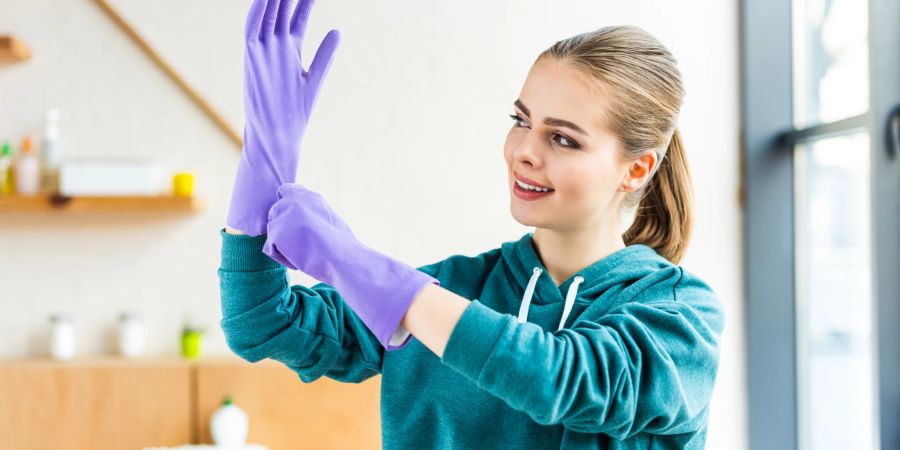 Frau mit Gummihandschuhen beim Putzen