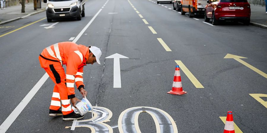 Ein Angestellter der Stadt Freiburg markiert im Oktober 2023 auf einer grösseren Freiburger Strasse Höchstgeschwindigkeit 30. (Archivbild)