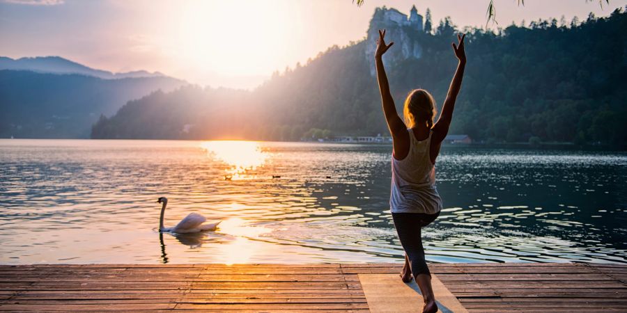 frau macht yoga auf steg, see, schwan, burg im hintergrund