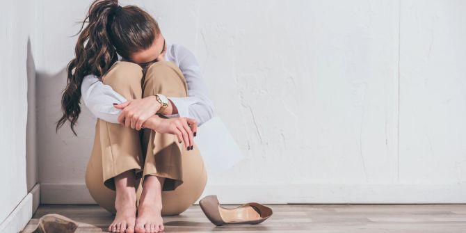 Aufgebrachte Frau sitzt auf dem Boden, Angststörung.