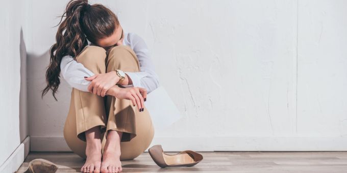 Wer lernt, seine Traumata zu integrieren, wächst an der Herausforderung. Aufgebrachte Frau sitzt auf dem Boden, Angststörung.
