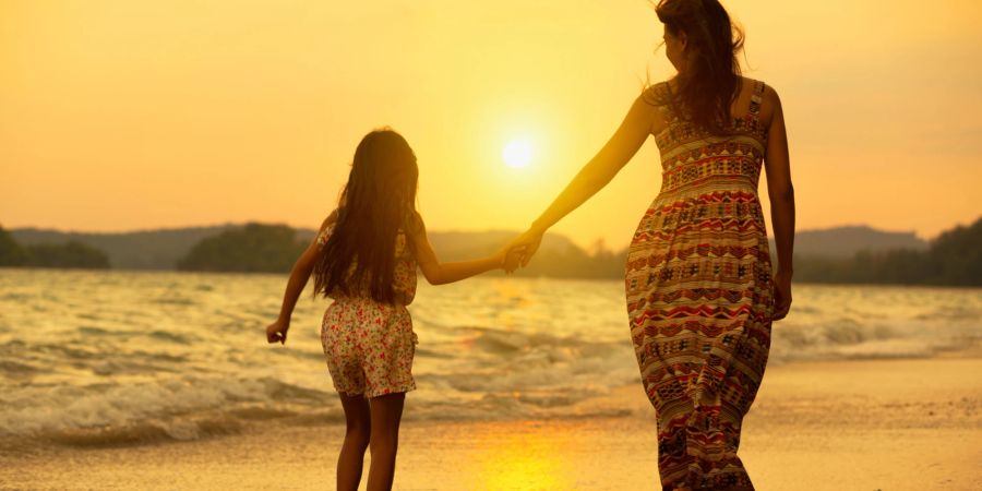 Mutter und Tochter am Strand im Sonnenuntergang.