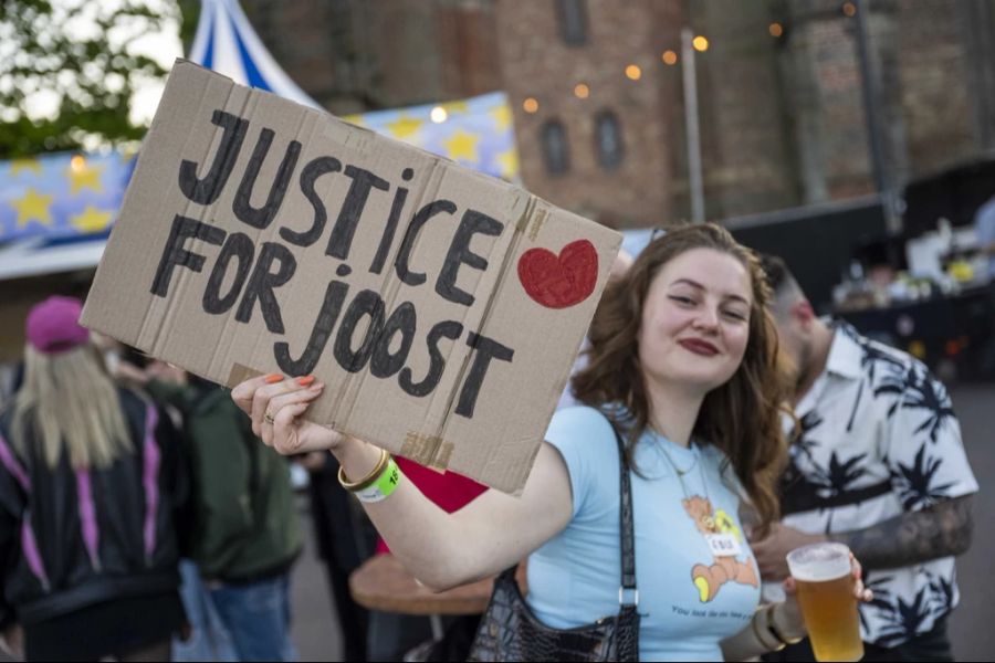 Eine Frau hält ein Schild auf, das Gerechtigkeit für Joost Klein fordert.