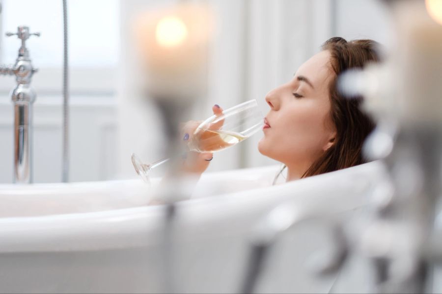 Frau trinkt Champagner in der Badewanne