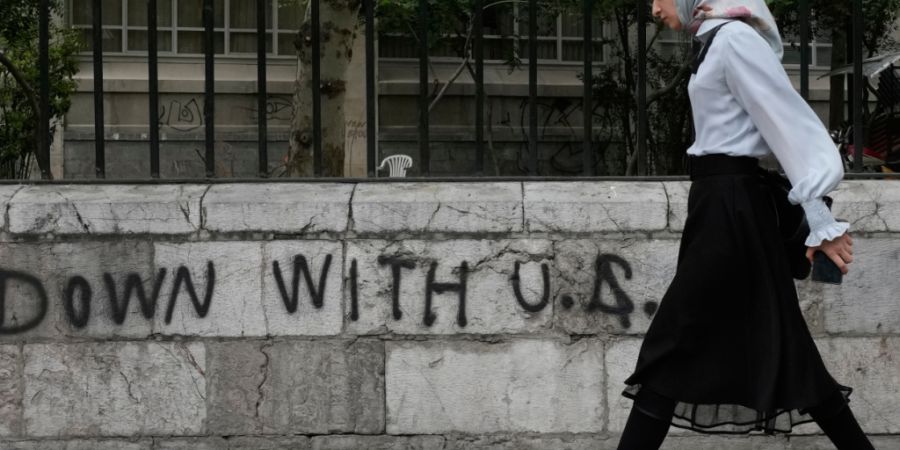 ARCHIV - Eine Frau geht an einem Anti-US-Graffiti vorbei, das an die Wand einer Universität im Zentrum von Teheran gemalt wurde. Foto: Vahid Salemi/AP/dpa/Symbolbild