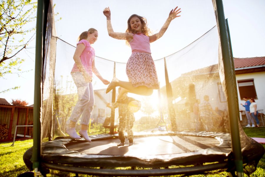 Kinder hüpfen auf einem Trampolin im Garten