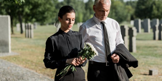 Mann und Frau auf einem Friedhof gehen zu einer Beerdigung