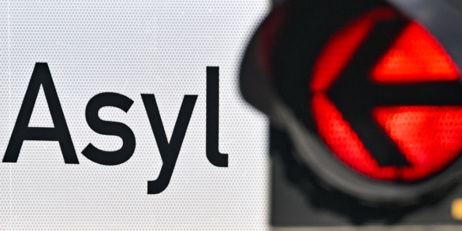 ARCHIV - Eine rote Ampel leuchtet vor dem Wort «Asyl» auf einem Wegweiser zur Erstaufnahme-Einrichtungen (EAE). Foto: Patrick Pleul/dpa/Archivbild