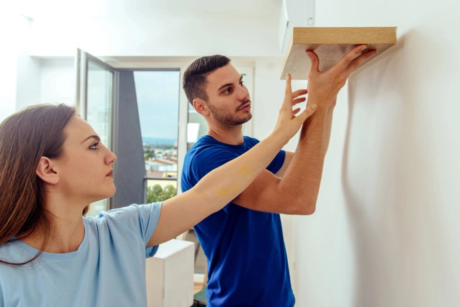 Mann und Frau befestigen Regal an der Wand