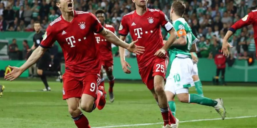 Thomas Müller (M) feiert mit Elfmeterschütze Robert Lewandowski (l) das 3:2 in Bremen. Foto: Christian Charisius