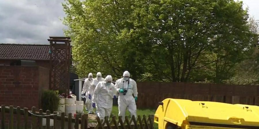 Mitarbeiter der Spurensicherung gehen durch den Garten des Wohnhauses, in dem eine 35-jährige Frau und ihr 4-jähriger Sohn tot aufgefunden wurden. Foto: -/TNN/dpa