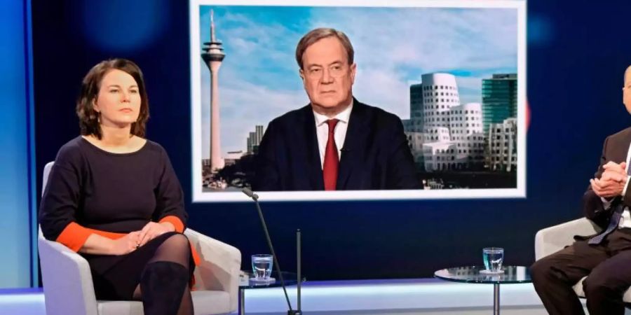 Unions-Kanzlerkandidat Armin Laschet wird auf einem Fernsehschirm gezeigt, während die Mitbewerbern von Grünen und SPD, Annalena Baerbock und Olaf Scholz im Fernsehstudio bei einer Diskussionsrunde des WDR-Europaforums in Berlin sitzen. Foto: Oliver Ziebe/WDR/dpa