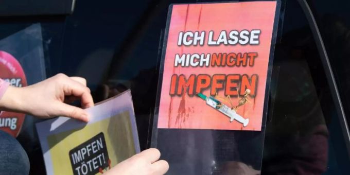 Eine Teilnehmerin eines Autokorsos stattet ihr Fahrzeug mit Anti-Impf-Schildern aus. Foto: Sebastian Kahnert/dpa-Zentralbild/dpa Eine Teilnehmerin eines Autokorsos stattet ihr Fahrzeug mit Anti-Impf-Schildern aus. Foto: Sebastian Kahnert/dpa-Zentralbild/dpa