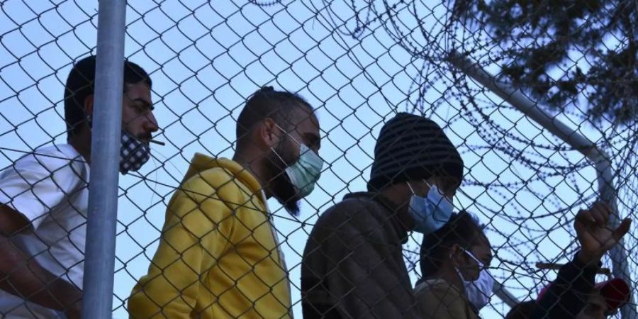 Migranten in einem Flüchtlingscamp am Hafen von Vathy auf der Insel Samos beobachten den Besuch der EU-Innenkommissarin Johansson. Foto: Michael Svarnias/AP/dpa