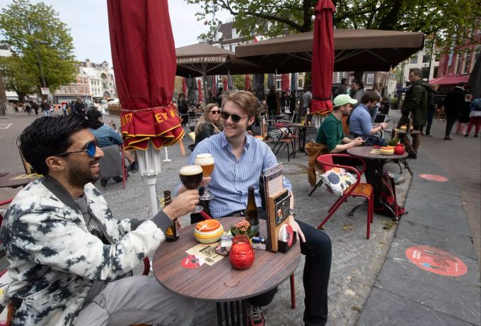 Männer stossen auf einer Café-Terrasse an. Die Niederlande haben einige Einschränkungen zur Eindämmung der Corona-Pandemie gelockert und unter anderem Bereiche der Aussengastronomie wieder geöffnet. Coronavirus - Niederlande