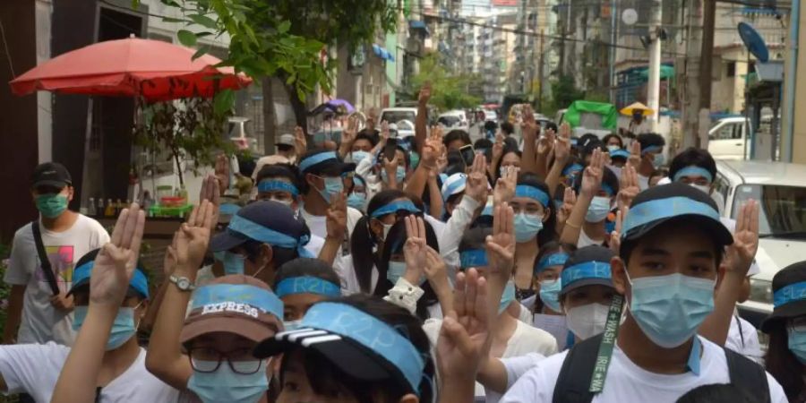 Menschen zeigen bei einer Demonstration den Drei-Finger-Gruss als Zeichen des Widerstands. Foto: -/AP/dpa