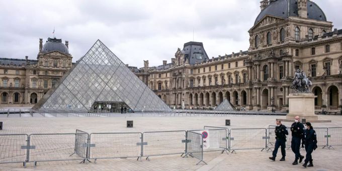 Der Louvre ist geschlossen, der Platz davor ist leer. Nur drei Polizisten gehen an einer Absperrung entlang. (Archivbild) Louvre Paris