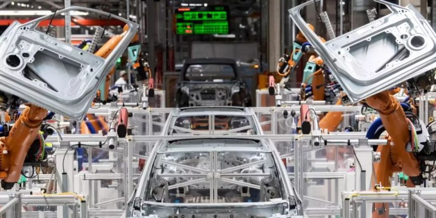 Im Karosseriebau des Volkswagen-Werkes in Sachsen montieren Roboter die Türen des VW ID.3. Eine umfassende Digitalisierung in den Bereichen Mobilität und Verkehr, industrielle Fertigung und bei Gebäuden kann einer Accenture-Studie zufolge fast die Hälfte zur Einhaltung der deutschen Klimaziele beitragen. Foto: Hendrik Schmidt/dpa-Zentralbild/dpa