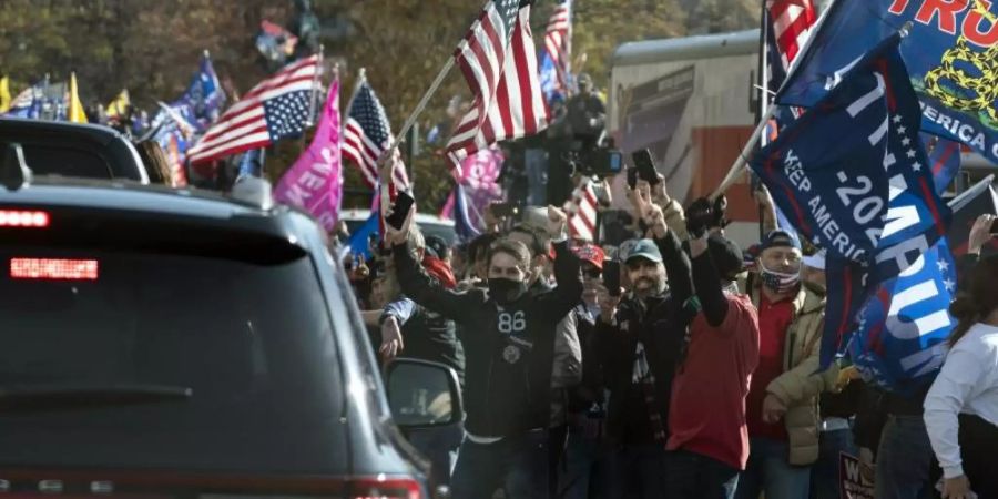 Der US-Präsident Trump fährt in einer Autokolonne an einer Gruppe von Anhängern vorbei, die zu dessen Unterstützung und gegen angeblich gefälschte Wahlergebnisse in der Nähe des Weissen Hauses demonstrieren. Foto: Evan Vucci/AP/dpa