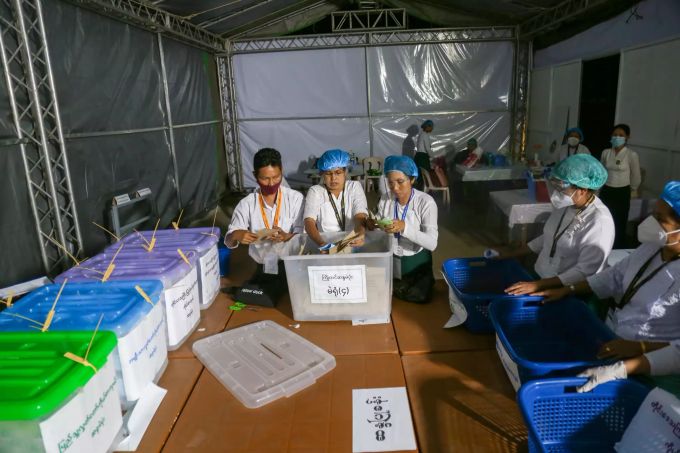 Wahlhelferinnen tragen Mund-Nasen-Bedeckungen und zählen im militärischen Wahllokal in Mandalay Stimmen aus. Parlamentswahl in Myanmar