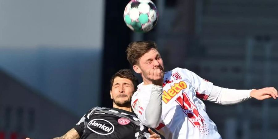 Der Düsseldorfer Matthias Zimmermann (l) und Andreas Albers von Jahn Regensburg kämpfen um den Ball. Foto: Armin Weigel/dpa