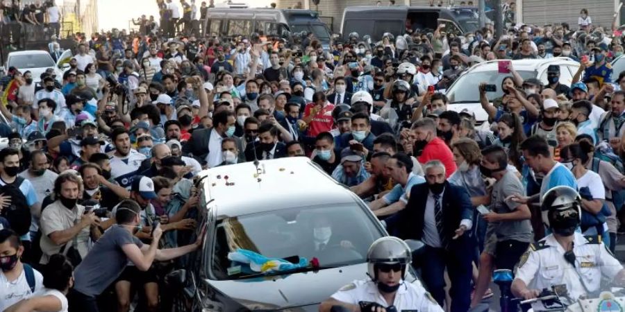 Nach dem Tod von Diego Maradona verlässt der Leichenwagen mit den sterblichen Überresten das Regierungsgebäude - begleitet von zahlreichen Fans. Foto: Ferrari Raul/telam/dpa