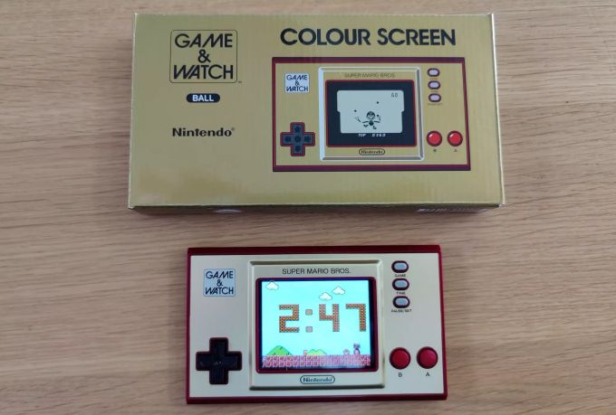 Die Uhrenanzeige des Nintendo Game & Watch: Super Mario Bros. sowie die Verpackung der Handheld-Konsole. Nintendo Game & Watch