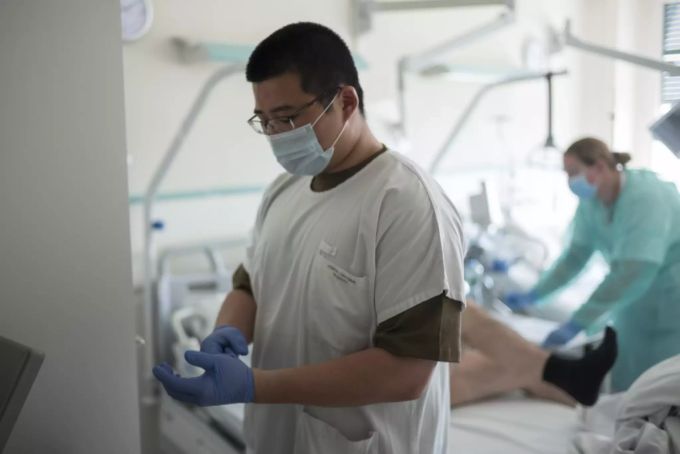 Soldat Liu Kelun, links, zieht sich die Schutzhandschuhe aus, nachdem er sich zusammen mit einer Pflegefachfrau um einen Covid-19 Patienten gekümmert hat, im Freiburger Spital (HFR), am Mittwoch, 8. April 2020 in Freiburg. Fünfzig Spital- und Sanitätssoldaten haben im Frühling in den Abteilungen Innere Medizin und Intensivpflege am Standort Freiburg eine Vielzahl von Aufgaben übernommen. Intensivpflege Armee Freiburg