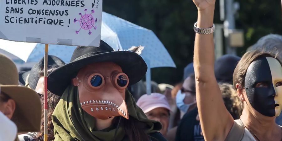 Eine Person (links) demonstrierte in Genf im Kostüm eines Pestdoktors. Die Schnabelmaske war im Mittelalter Teil der Arztausrüstung.