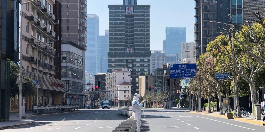 Ein Mann in einem Schutzanzug steht inmitten leerer Strassen in einem abgesperrten Gebiet im Bezirk Jingan im Westen von Shanghai.