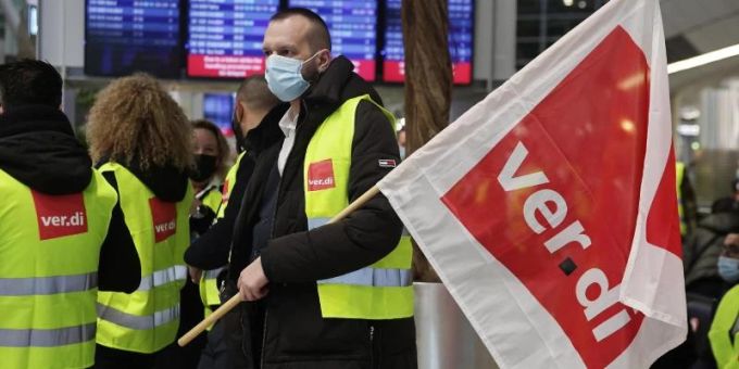 Ein Streikender hält auf einem Flughafen eine Verdi-Flagge. (Archivbild) Foto: David Young/dpa Streikender