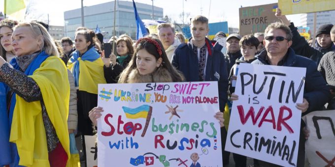 Demonstranten halten Plakate, während sie während einer Kundgebung auf dem Platz der Vereinten Nationen in Genf gegen Russlands massiven Militäreinsatz gegen die Ukraine protestieren. Friedensdemo in Genf