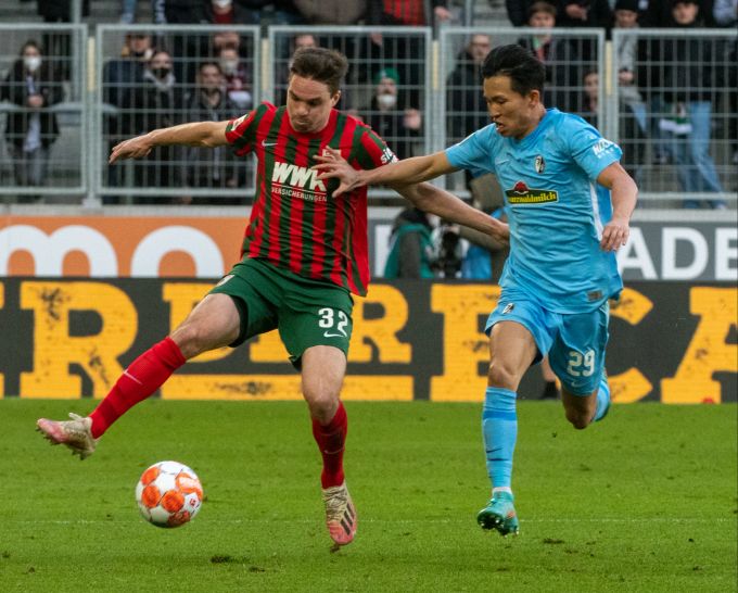 Augsburgs Raphael Framberger (l) und Freiburgs Woo-Yeong Jeong kämpfen um den Ball. FC Augsburg SC Freiburg
