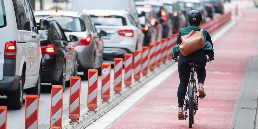 Eine Fahrradfahrerin fährt auf einer Fahrradspur an einer Strasse. Die Sorge vor den Folgen der Klimakrise ist für die Menschen in Deutschland die stärkste Motivation, ihr eigenes Mobilitätsverhalten zu ändern.