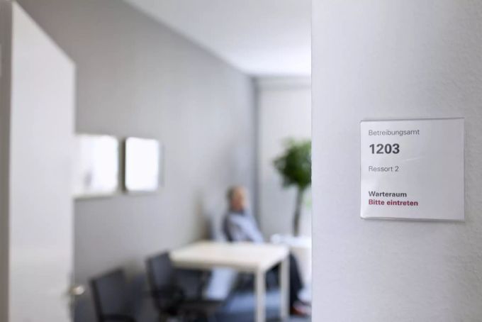 Ein Mann sitzt im Warteraum eines Betreibungsamtes. Coronavirus