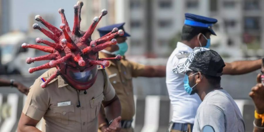 Ein indischer Polizist mit einem Corona-Helm bei einer Verkehrskontrolle