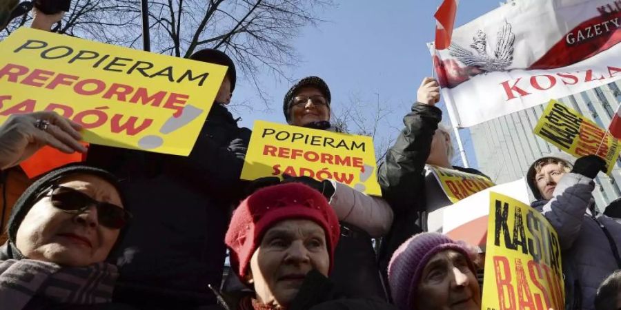 Unterstützer der rechten Regierung Polens halten auf einer Demonstration für eine Justizreform Plakate in die Höhe (Archiv). Foto: Czarek Sokolowski/AP/dpa