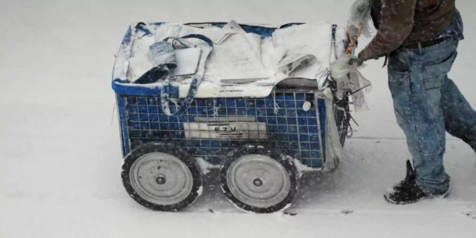 Arbeiten zum Mindestlohn: Ein Zeitungszusteller ist am frühen Morgen bei dichtem Schneetreiben in Berlin unterwegs. Foto: Daniel Reinhardt/dpa Zeitungszusteller