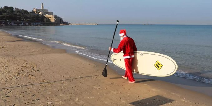 Ein als Weihnachtsmann verkleideter Christ geht am Strand von Tel Aviv spazieren. Christmas in Israel
