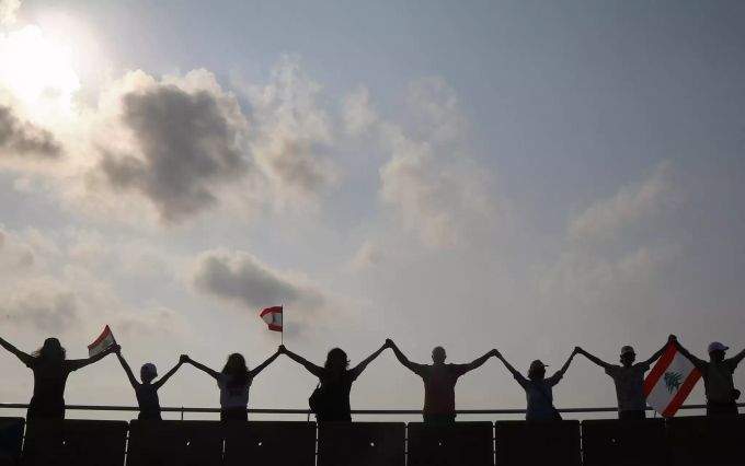 Libanesen halten libanesische Flaggen während sie eine Menschenkette als Zeichen nationaler Einheit bilden. Proteste im Libanon